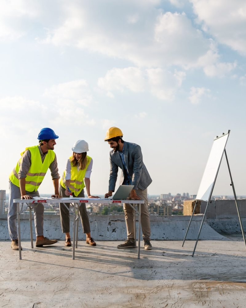 Construction concept. Group of engineers and architects working at construction site with blueprint