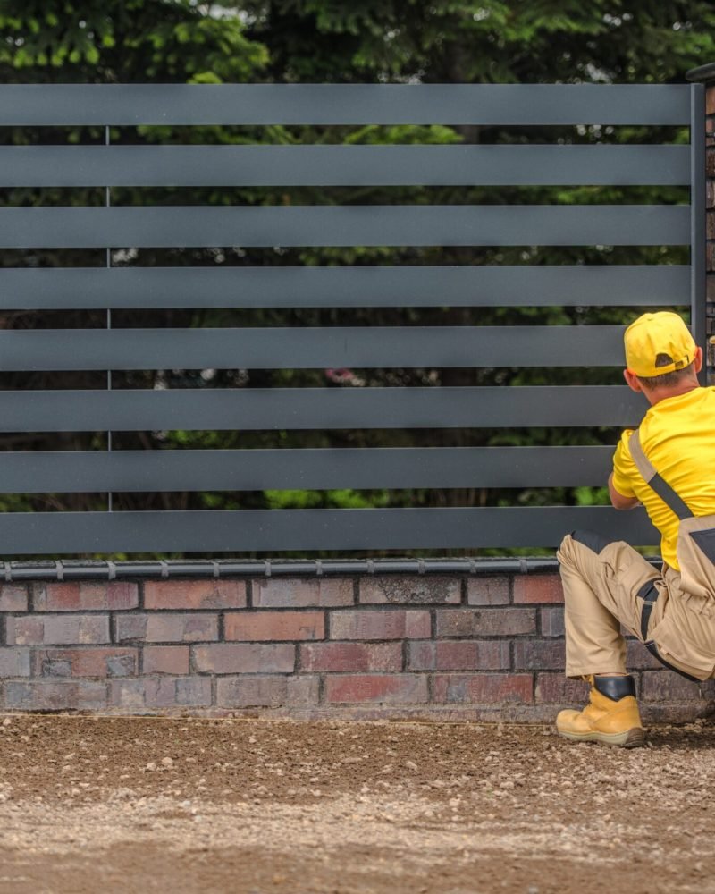 Residential Stylish Metal Panels Fence Building by Professional Fencing Contractor Worker.